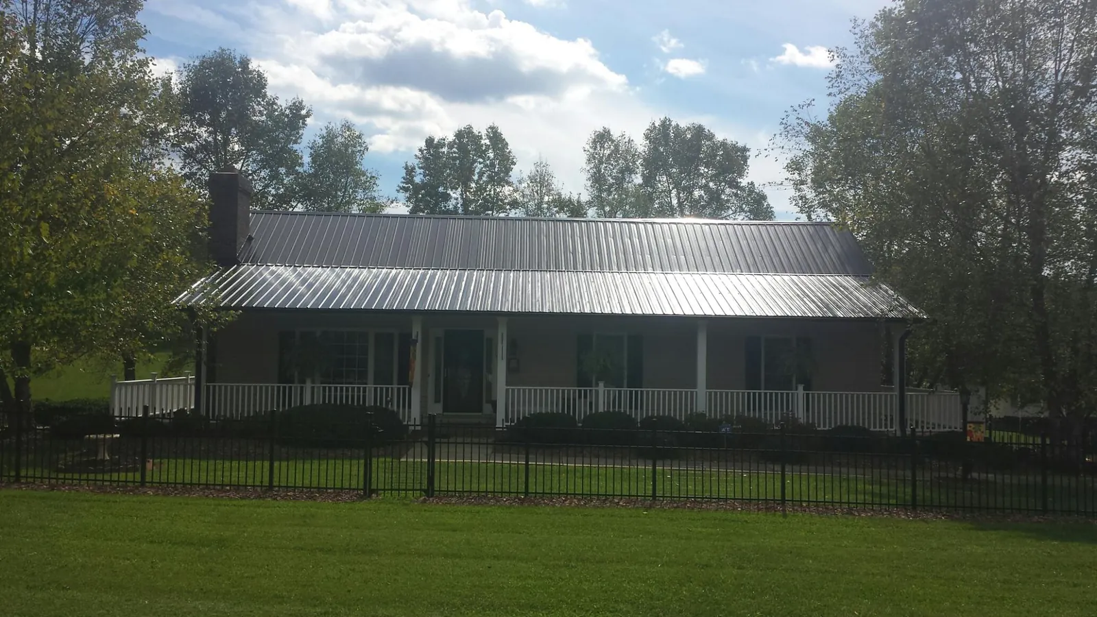 Gray metal roof on a brick ranch with a full width front porch — Gutter Guard Installation work by our crew in Gardiner